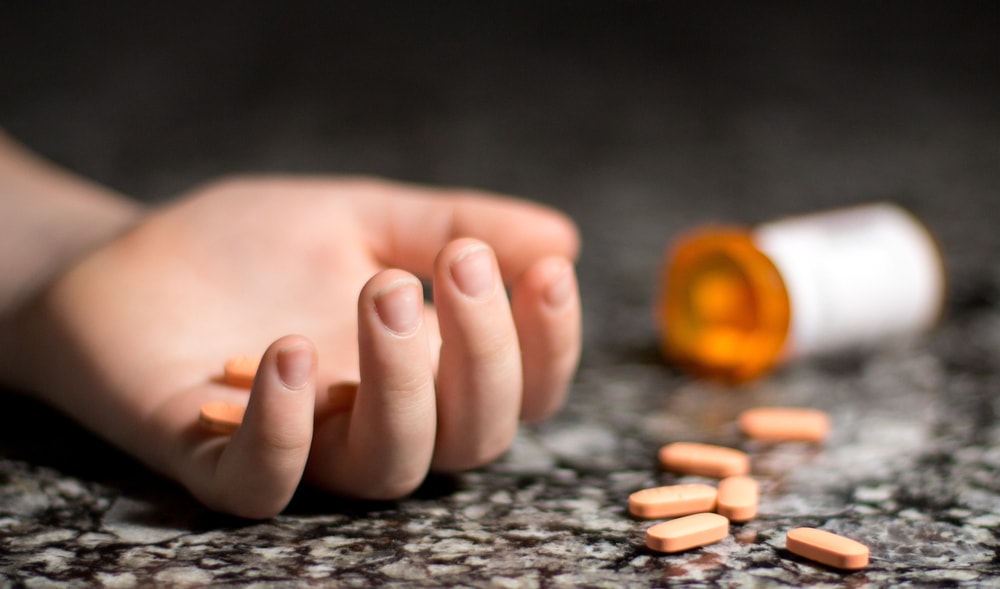 Hand with Bottle of Spilled Pills Due to Suicide